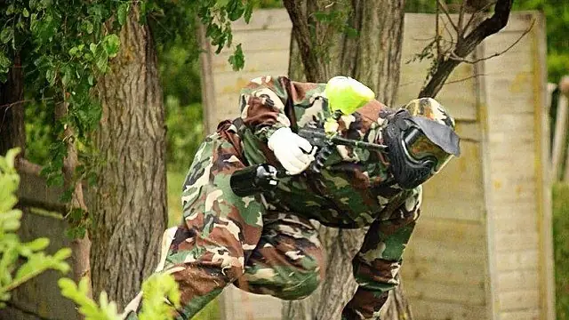 Игрок в камуфляже на полосе препятствий пейнтбольного поля